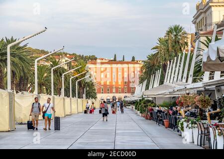 Split, Croatia - Aug 15, 2020: Tourists on esplanade by coean in early morning Stock Photo