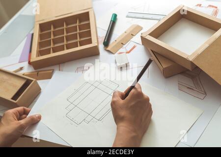 Designer draws a mockup for crafting eco cardboard box. Stock Photo