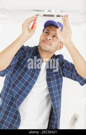 handyman fixate a lamp on the ceiling Stock Photo