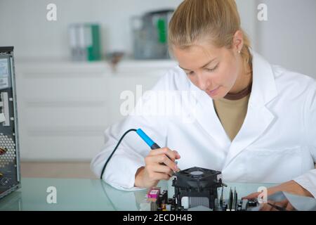 young woman solders and adjusts electronic device Stock Photo