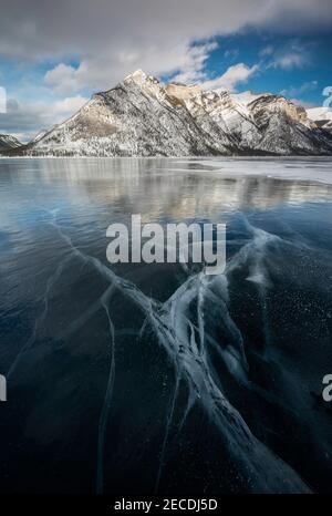 Lightning shaped ice cracks formed on the frozen Lake Minnewanka in Banff National Park during an afternoon January day. Stock Photo
