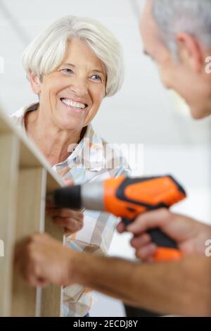 woman smiling at man using an electronic drill Stock Photo