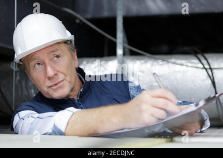 mature man construction worker reading on clipboard Stock Photo