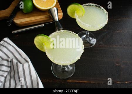 Hemingway Daiquiris (Papa Dobles) Garnished with Limes: Two rum, lime, and grapefruit cocktails served in sugar-rimmed coupe glasses Stock Photo