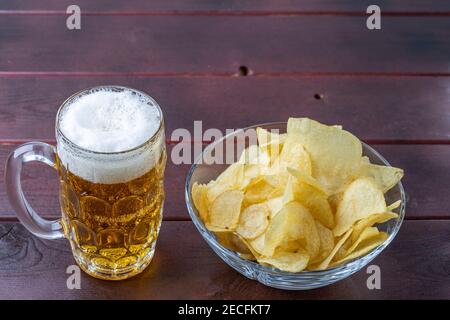 Close up view of beer in glass mug and cup of potato chips. Stock Photo