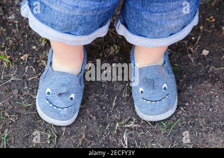 Cute shark shoes on a little boy's legs standing on dirt - view from top with bottom of his blue jean shorts showing Stock Photo