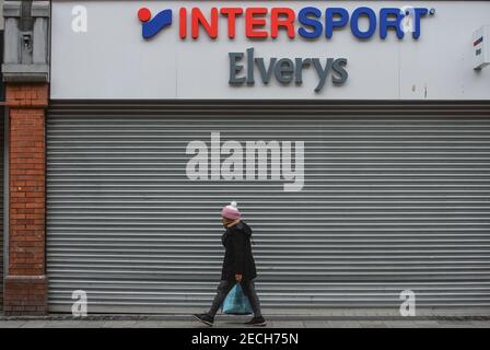 Dublin, Ireland. 13th Feb, 2021. A woman wearing a face mask walks past a closed InterSport shop on Henry Street. Credit: SOPA Images Limited/Alamy Live News Stock Photo
