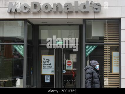 Dublin, Ireland. 13th Feb, 2021. A man wearing a face mask walks past a closed McDonald's store in Dublin. Credit: SOPA Images Limited/Alamy Live News Stock Photo