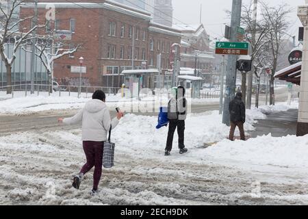 Seattle, Washington, USA. 13th February, 2021. Pedestrians walk through heavy slush in Seattle’s Chinatown–International District during a winter storm. Lunar New Year celebrations, already scaled back due to the coronavirus pandemic, were postponed due to ongoing heavy snow in the region. Credit: Paul Christian Gordon/Alamy Live News Stock Photo