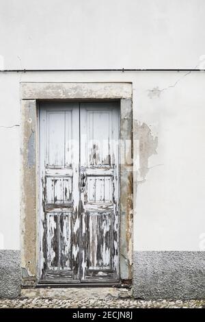 Vintage front door with shubby paint and wall with old weathered damaged house facade Stock Photo