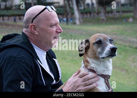 A man, Robert O'Connor, petting his dog Chandler at a park in Placentia, California, USA. Stock Photo