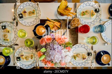 A top view of various delicious food with drinks on a wedding table with a bouquet of flowers Stock Photo