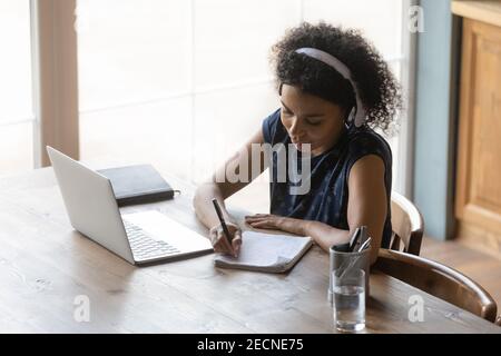 Top view African American woman in headphones taking notes Stock Photo