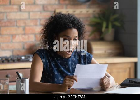Close up overjoyed African American woman reading letter Stock Photo