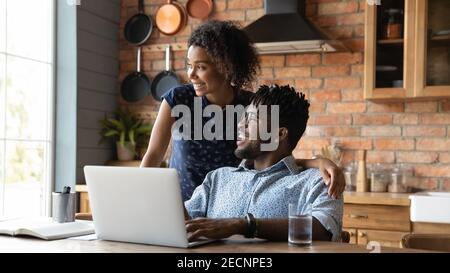 Close up happy dreamy African American couple distracted from laptop Stock Photo