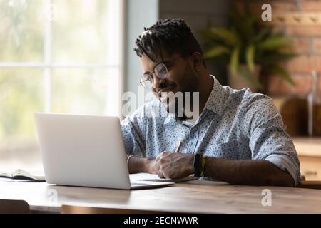 Close up African American man using laptop, taking notes Stock Photo