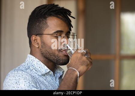 Close up thirsty African American man wearing glasses drinking water Stock Photo
