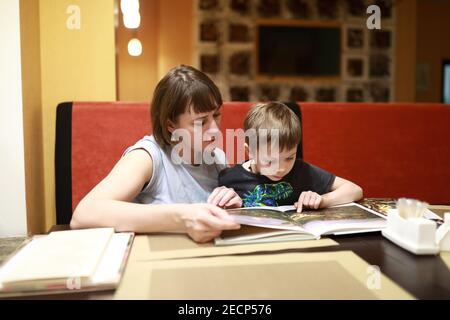Portrait of mother with son examines magazine in cafe Stock Photo