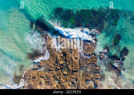 Catherine Hill Bay aerial view of waves breaking on the rocky shore with clear water showing the rocks below the waterline. Stock Photo