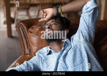 Close up unhappy depressed African American man lying on couch Stock Photo