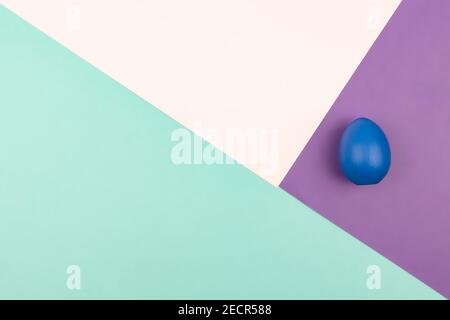 Abstract geometric paper background of pastel pink and purple colors with blue easter egg. Copy space for design. Stock Photo