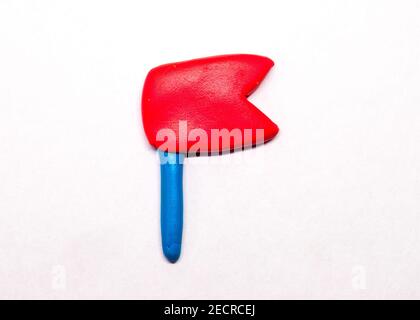 Red flag or pointer isolated. Modelling clay navigation sign on white background. Navigation flag in naive nursery style. Children hobby modeling. Han Stock Photo