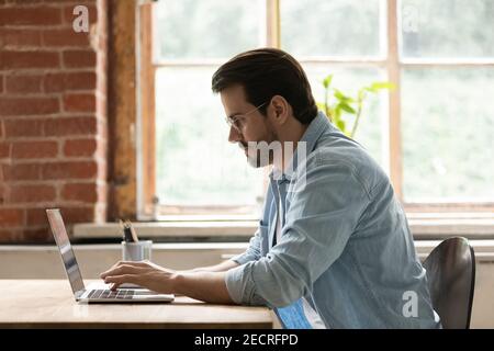 Focused male employee work on laptop in office Stock Photo