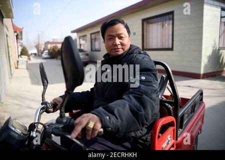 (210214) -- YINCHUAN, Feb. 14, 2021 (Xinhua) -- Zhang Junming goes shopping on an electronic tricycle at a market near his new residence at the Binhe Jiayuan relocation site one day before the Chinese Lunar New Year in Yinchuan, northwest China's Ningxia Hui Autonomous Region, Feb. 11, 2021. Zhang Junming, 55, once lived in Hongbaiyang Township, an economic backwater in southern Ningxia. When he was young, Zhang had been severely injured in an accident, and hence suffered from leg disabilities that prevented him from seeking job opportunities in the big cities. So he and his family had to scr Stock Photo