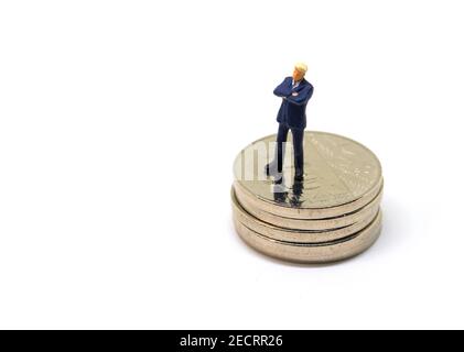 Businessman figurine on coins. Business man stand on money concept. Corporation financial turnover and profit. Financial pyramid. Businessman proud of Stock Photo