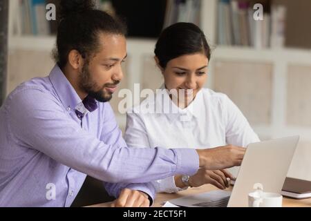 Smiling multiethnic colleagues work together on computer Stock Photo