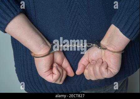 Men's hands in handcuffs chained from behind Stock Photo