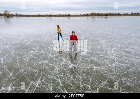 People ice skate on frozen flooded fields near Ely in Cambridgeshire, as the cold snap continues to grip much of the nation. Picture date: Saturday February 14, 2021. The Cambridgeshire Fens were the birthplace of British speed skating and require four nights of frost, with a temperature of -4 or colder and little or no thawing during the days inbetween, to make ice strong enough to skate on. Stock Photo
