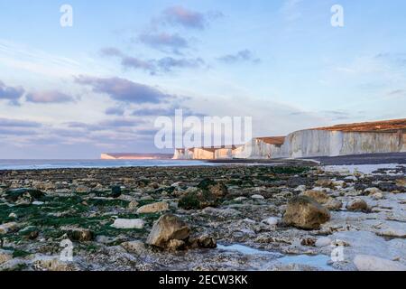 Low tide and early morning at Birling Gap with sunlight catching the chalk cliffs of the seven sisters in east Sussex south east England