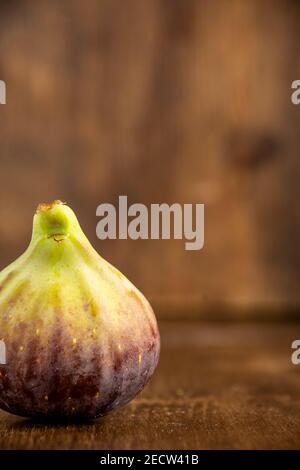 View of a purple fig, on table and defocused wooden background, vertically, with copy space Stock Photo