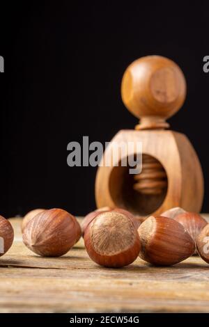 Close-up of hazelnuts on rustic wooden table and wooden nutcracker in the background, with selective focus, black background, horizontal, with copy sp Stock Photo