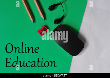 Education concept in reference to online learning. Mouse, pencil sharpener, pencils, earphones with text 'Online Education'. Selective focus points Stock Photo