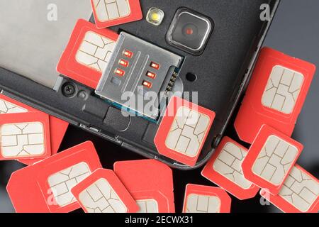 Cell phone and many red sim cards, closeup Stock Photo