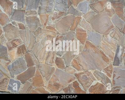 Wall with decorative rough granite masonry of various shapes. Closeup photo. Stock Photo