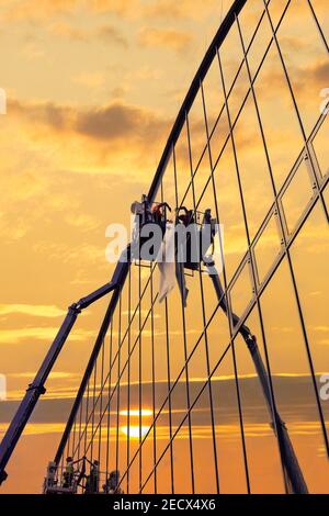 Two construction workers working at height on skyscraper. Professionally people work on billboard advertising at height. Stock Photo