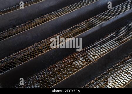 full frame background of wet iron grate stairs in diagonal perspective composition. Stock Photo