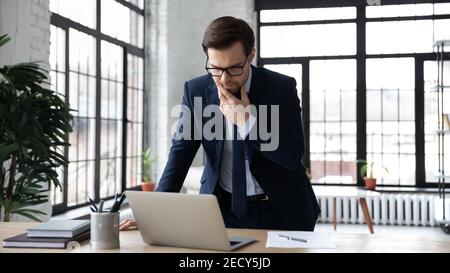 Pensive businessman look at laptop screen solving problem Stock Photo