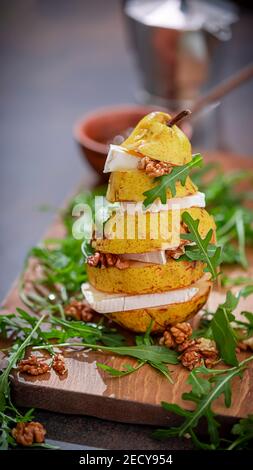 Tower pear with cheese, walnuts, arugula, with honey on a dark wooden background. Healthy vegetarian food. Selective focus Stock Photo