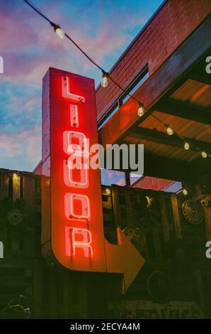 A vertical shot of a retro neon sign ''Liquor'' pointing the way to a bar Stock Photo