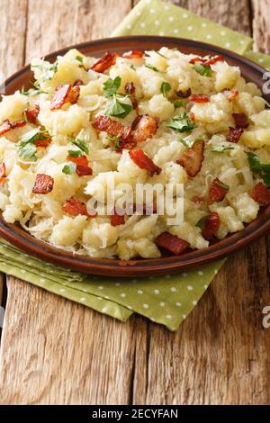 Strapacky Slovak potato dumplings with steamed sauerkraut and bacon closeup in the plate on the table. vertical Stock Photo