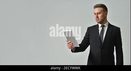 Business person looking attentively in digital tablet on gray background Stock Photo