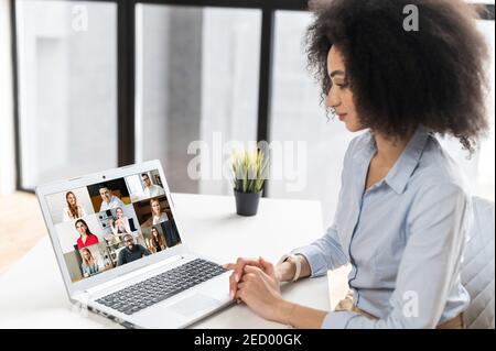 Multiracial woman sitting at the laptop, chatting with friends or colleagues via video meeting,discussing the new project, teaching online,making Stock Photo