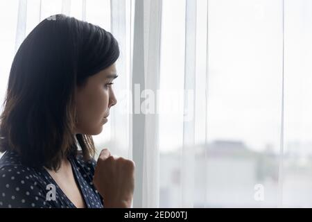 Anxious sad young asian woman crying alone looking at window Stock Photo