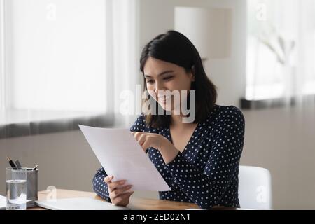 Smiling asian female review paper report satisfied with good results Stock Photo