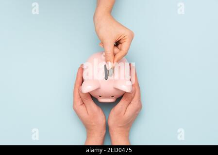 Woman puts a coin in a piggy bank. Budget, money savings concept Stock Photo