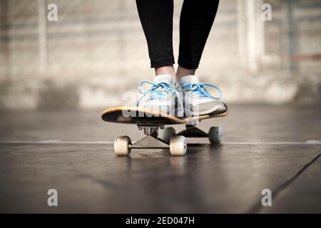 close-up shot of feet of a young woman skateboarding outdoors Stock Photo